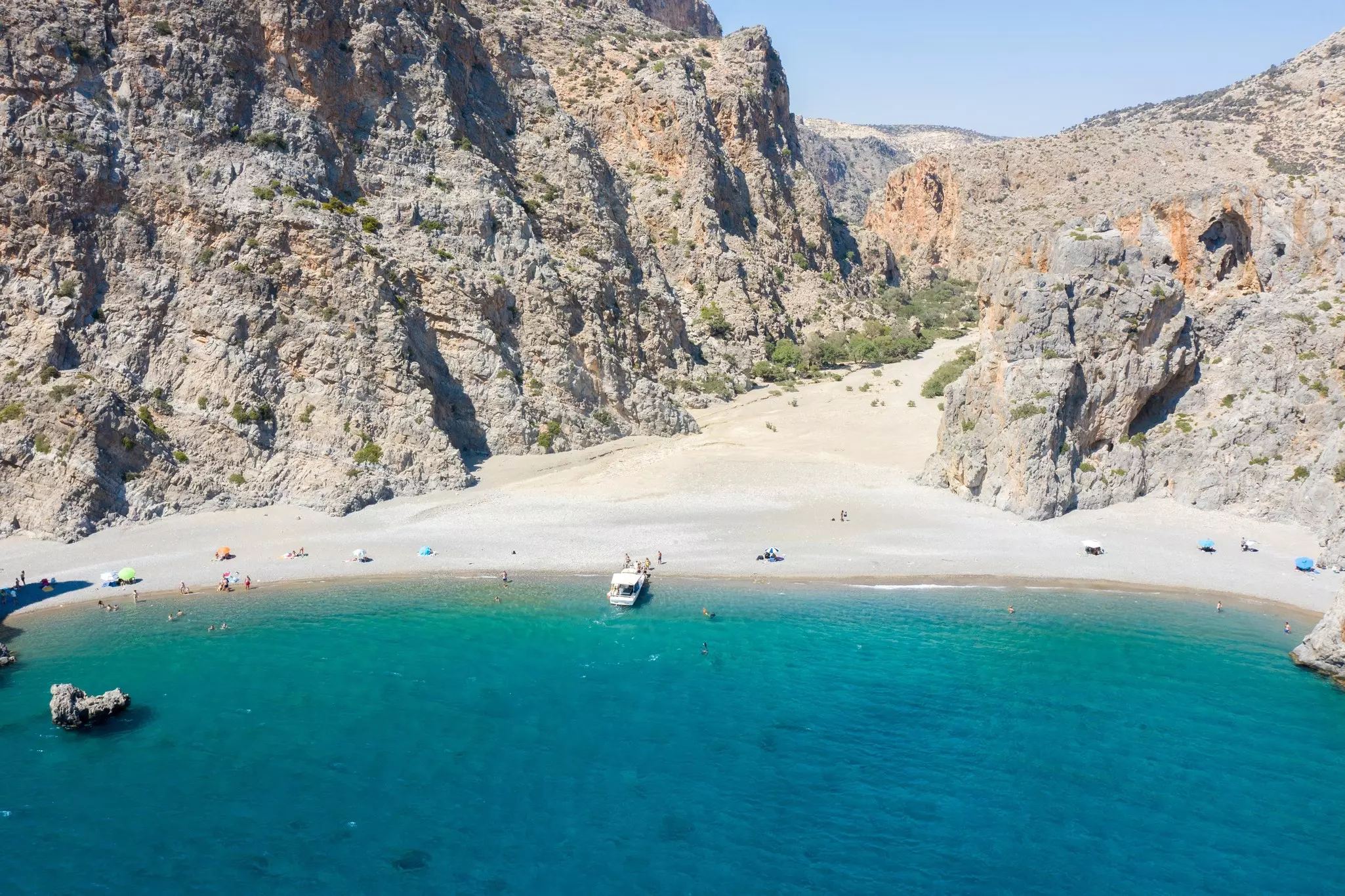 A sparsely populated beach with craggy mountains near its shore