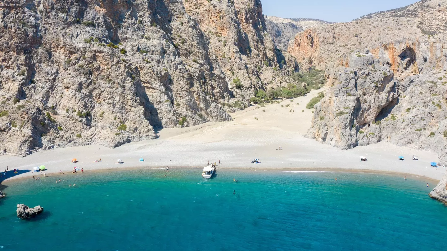 A sparsely populated beach with craggy mountains near its shore