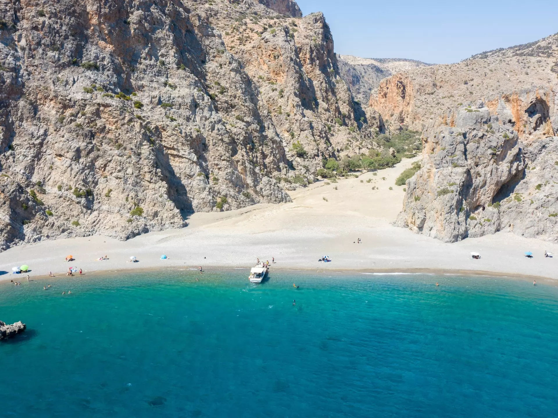 A sparsely populated beach with craggy mountains near its shore