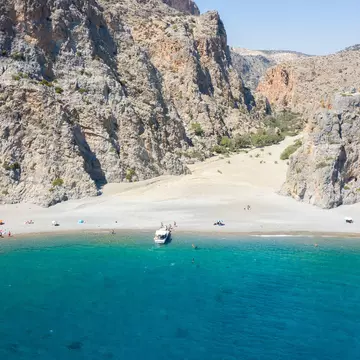 A sparsely populated beach with craggy mountains near its shore