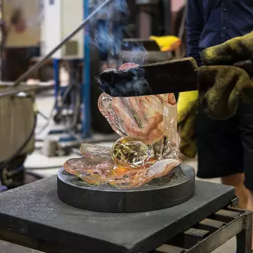 KOSTA, SWEDEN - MARCH 12 2020: Man makes a glass shell with a pearl out of just blown liquid and glowing hot colored glass in Kosta glassworks in Sweden; Shutterstock ID 1685666926;