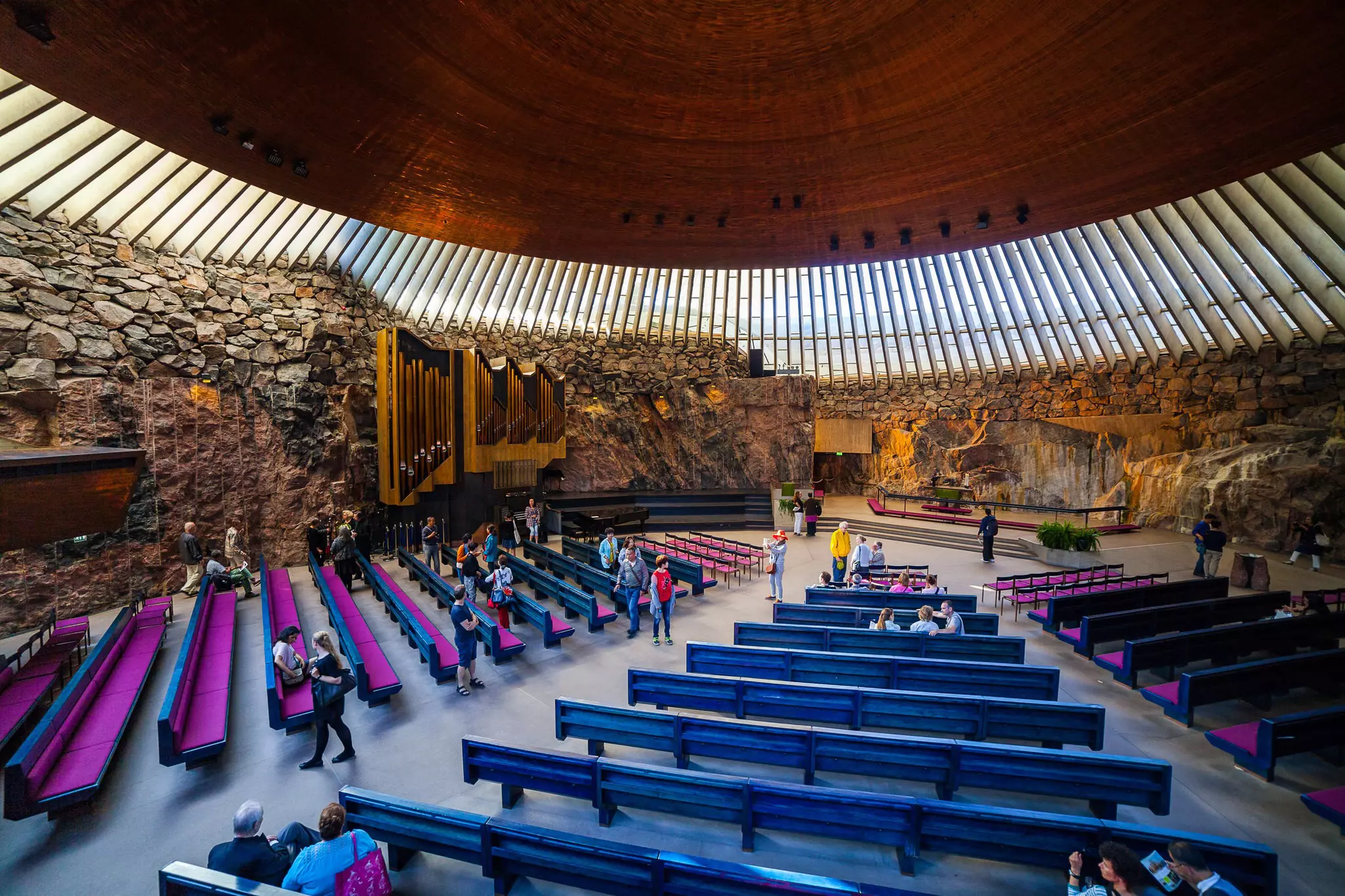 People in a large round concert hall with an organ against one wall. The Temppeliaukion Kirkko, Helsinki 