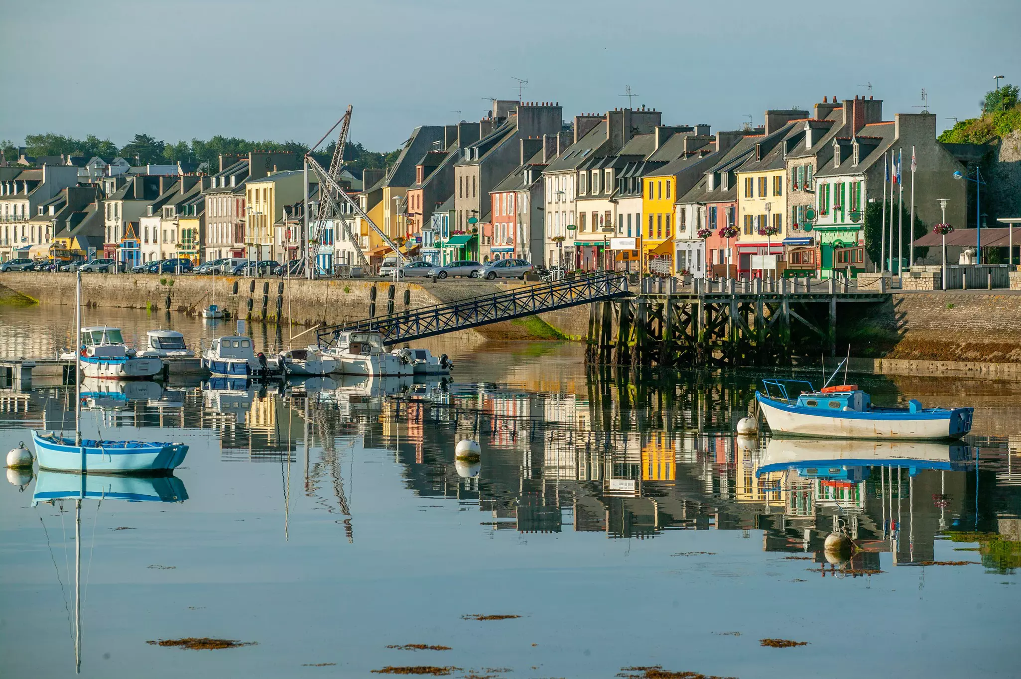 A view of colored houses along the waterfront of a fishing village. Boats are moored at low tide in the harbor.