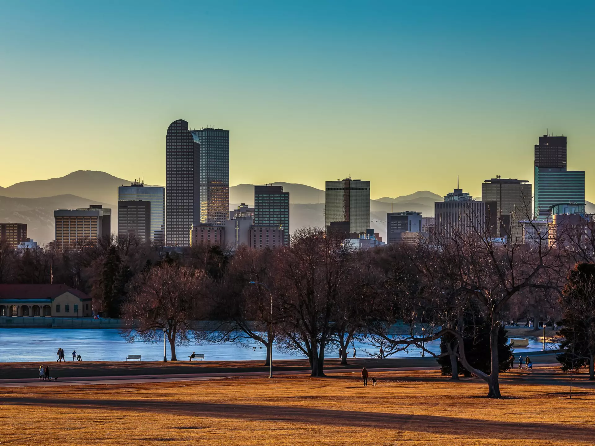 Parkland gives way to a river and a city. In the distance is a range of mountains