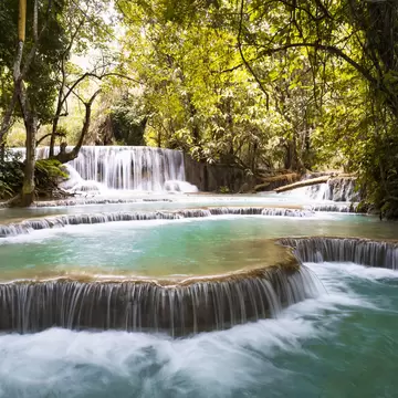 A waterfall surrounded by jungle cascades into a series of turquoise pools.