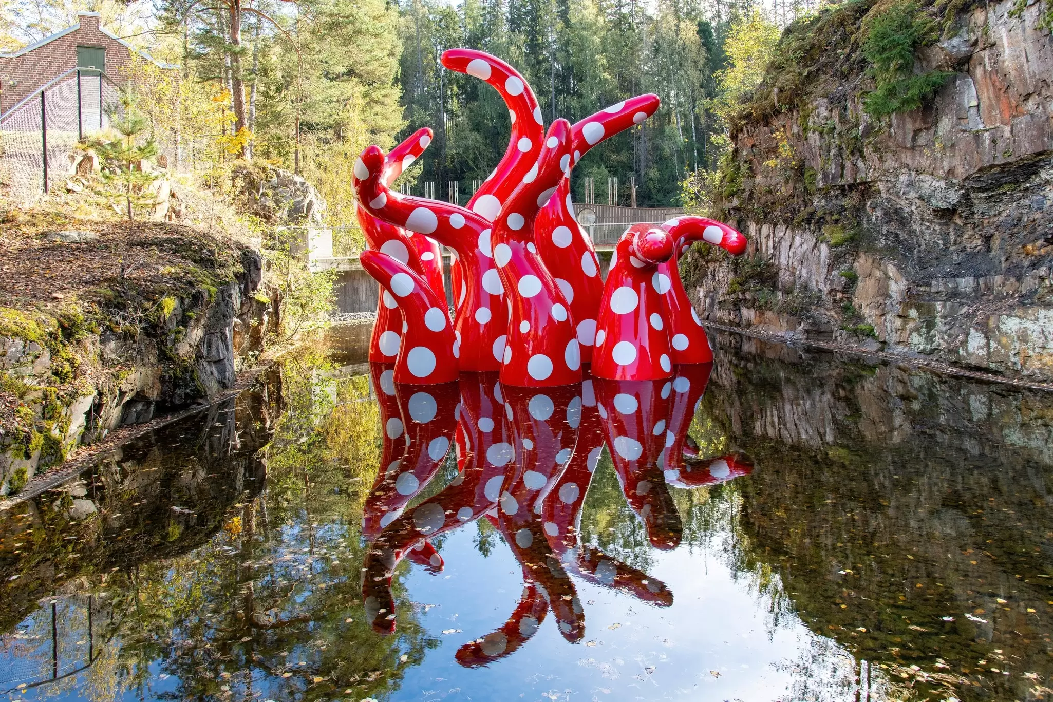 A series of red tentacles with white dots reach out of the water in Kistefos sculpture park, near Oslo, Norway.
