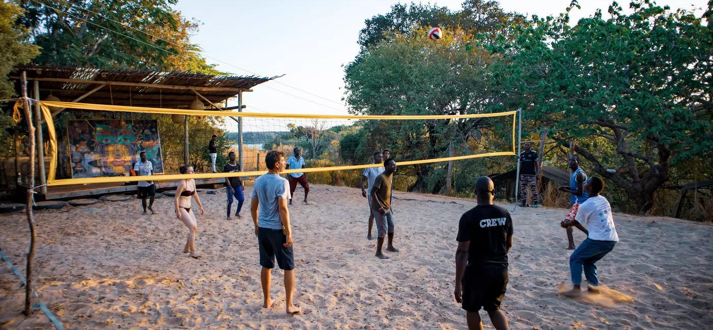 A group of people play volleyball on a sandy court