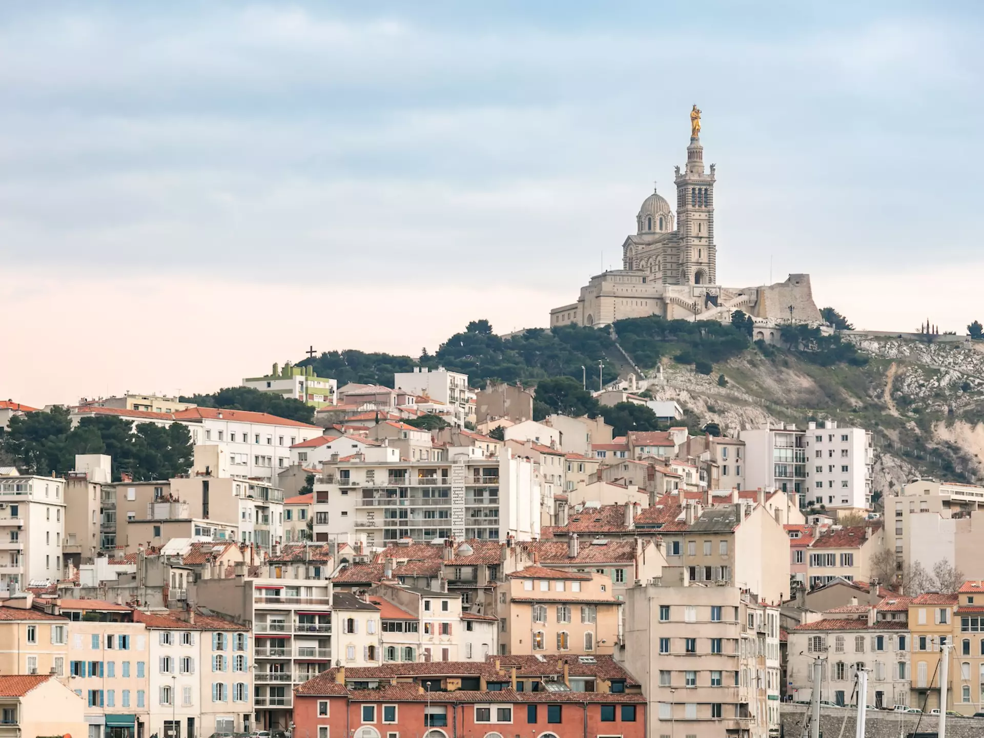 Buildings with Notre Dame de la Garde church on a hill in the distance, Marseille, France