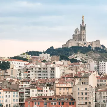 Buildings with Notre Dame de la Garde church on a hill in the distance, Marseille, France