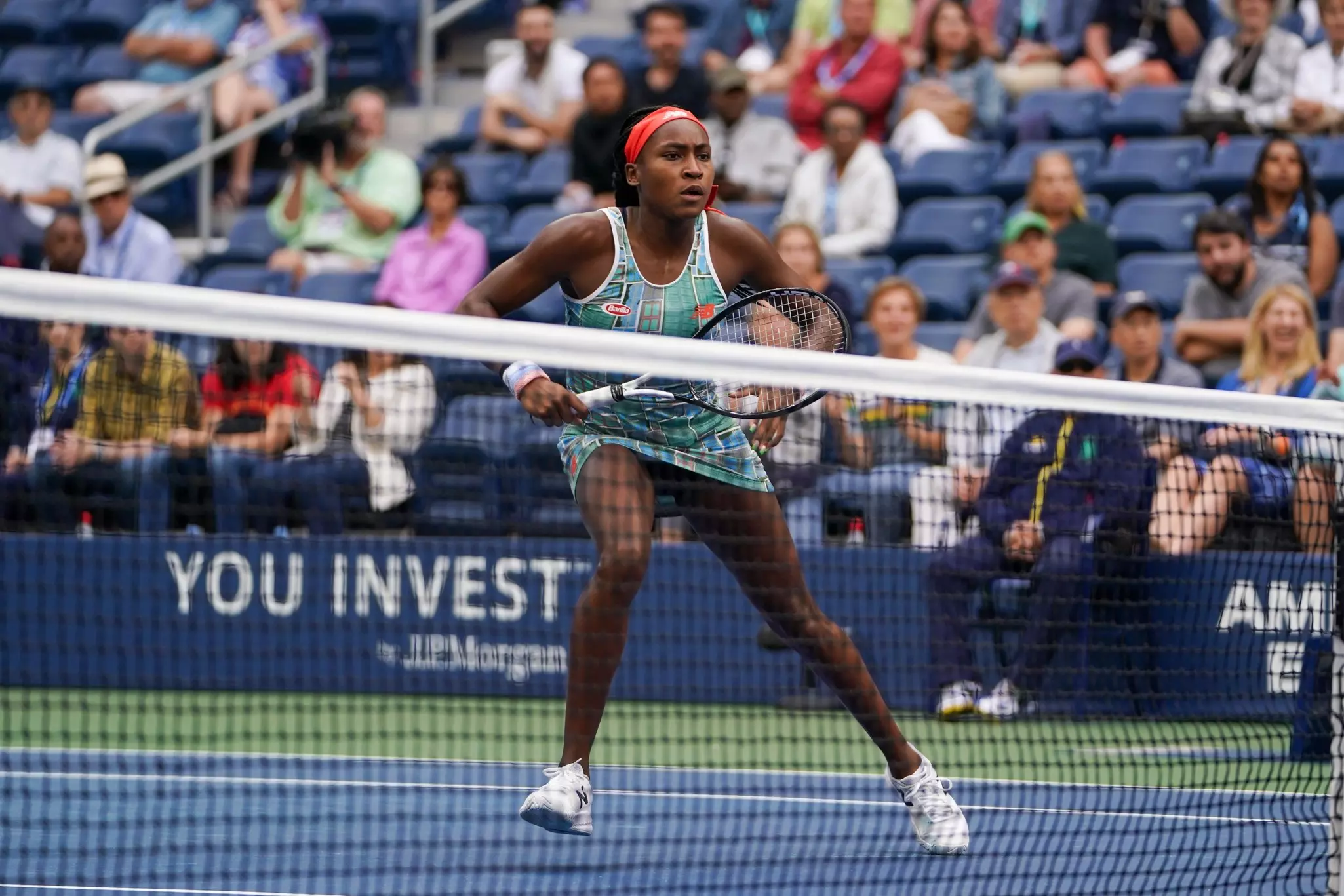 A young woman and professional tennis player, 15-year-old Coco Gauff, in action on the courts in the 2019 US Open surrounded by seated spectators.