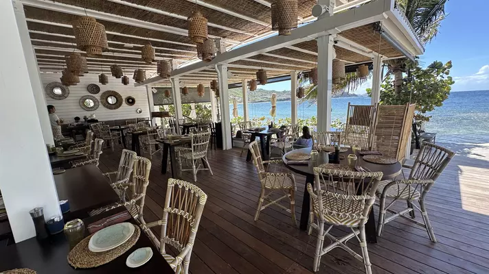 Wicker chairs arranged around wooden tables on an outside terrace