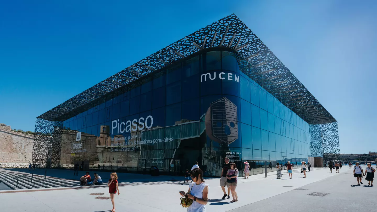 The large glass-and-steel exterior of MuCEM, with people walking by
