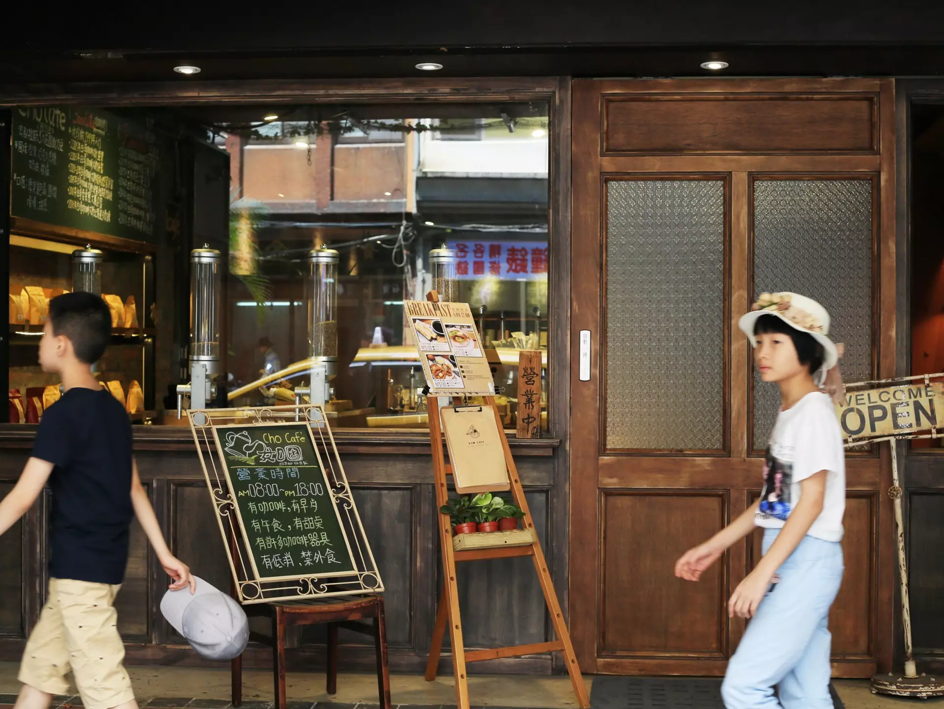 Two people walk past a small cafe in Taipei