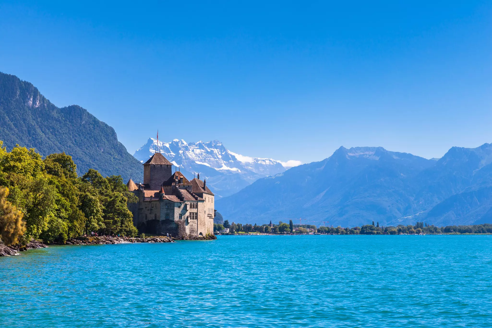 A view of Chillon Castle on the lake side of Geneva lake, with the peaks of Dents du Midi in the background