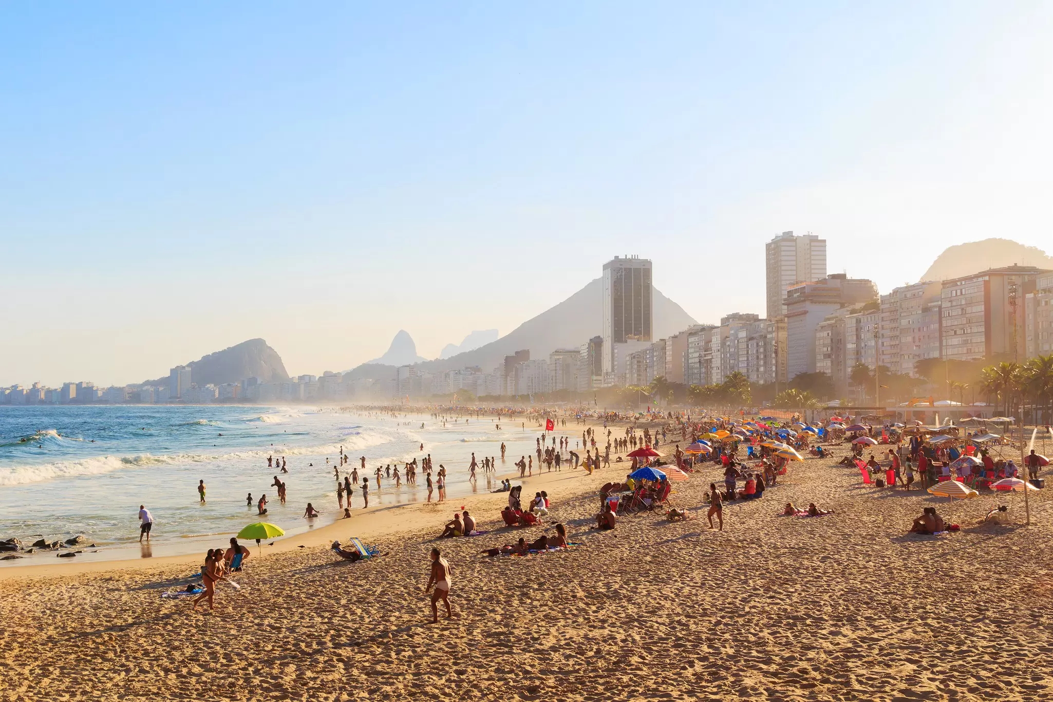 People resting on Copacabana Beach during sunset in Rio de Janeiro, Brazil.