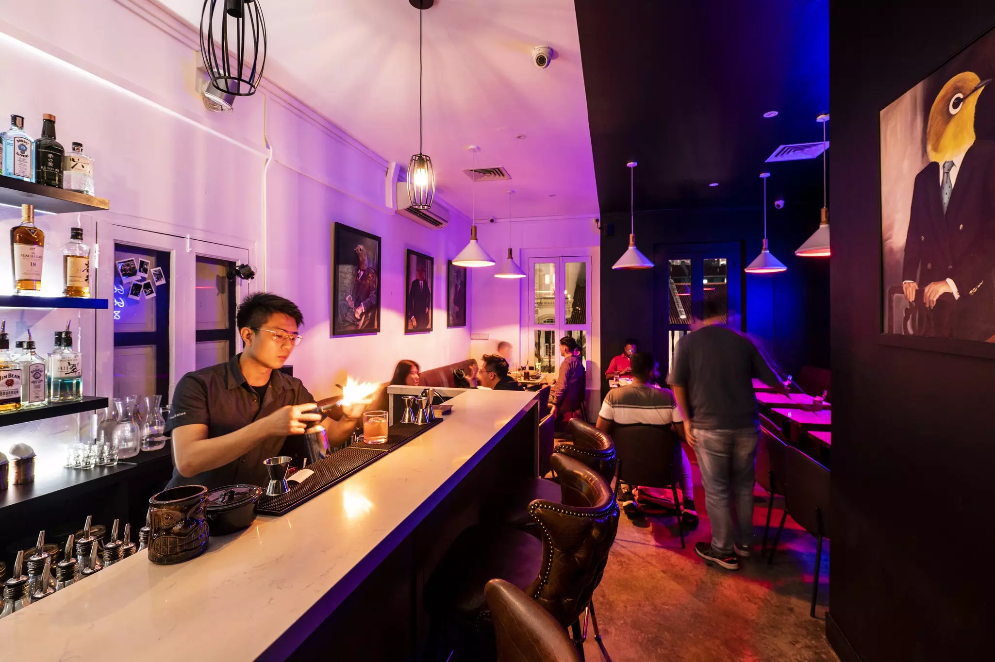A bartender behind a counter at a stylish restaurant prepares an elaborate cocktail