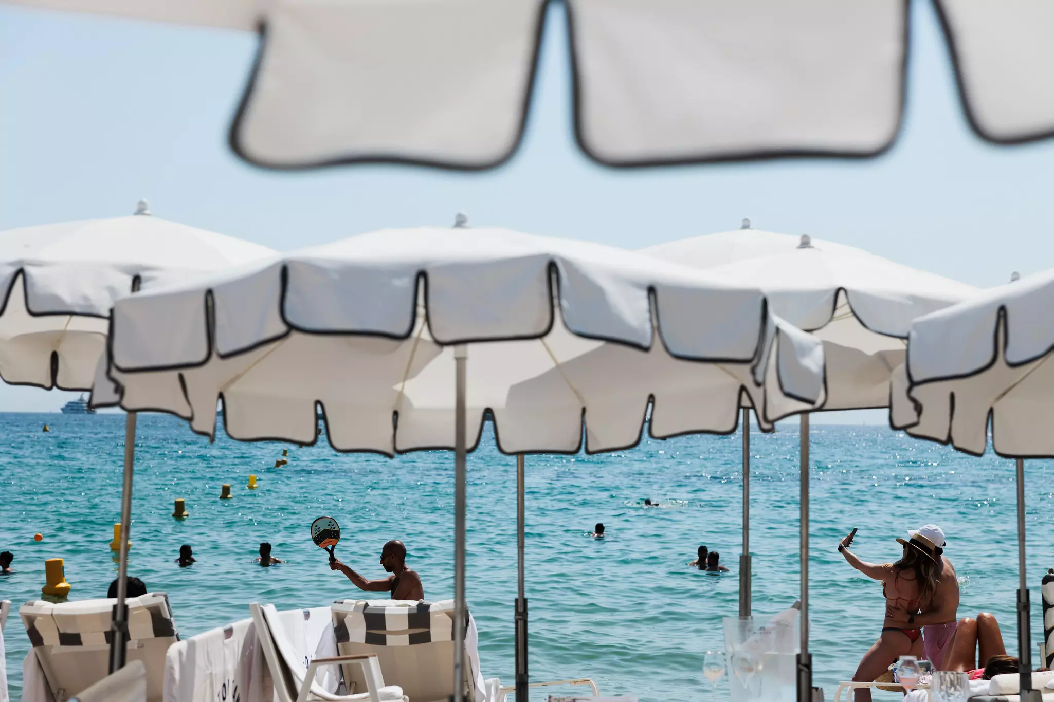 A lux beach set up at the Carlton Cannes hotel in Cannes, France. Umbrellas and loungers, people playing paddle in the sand. Sunny day.