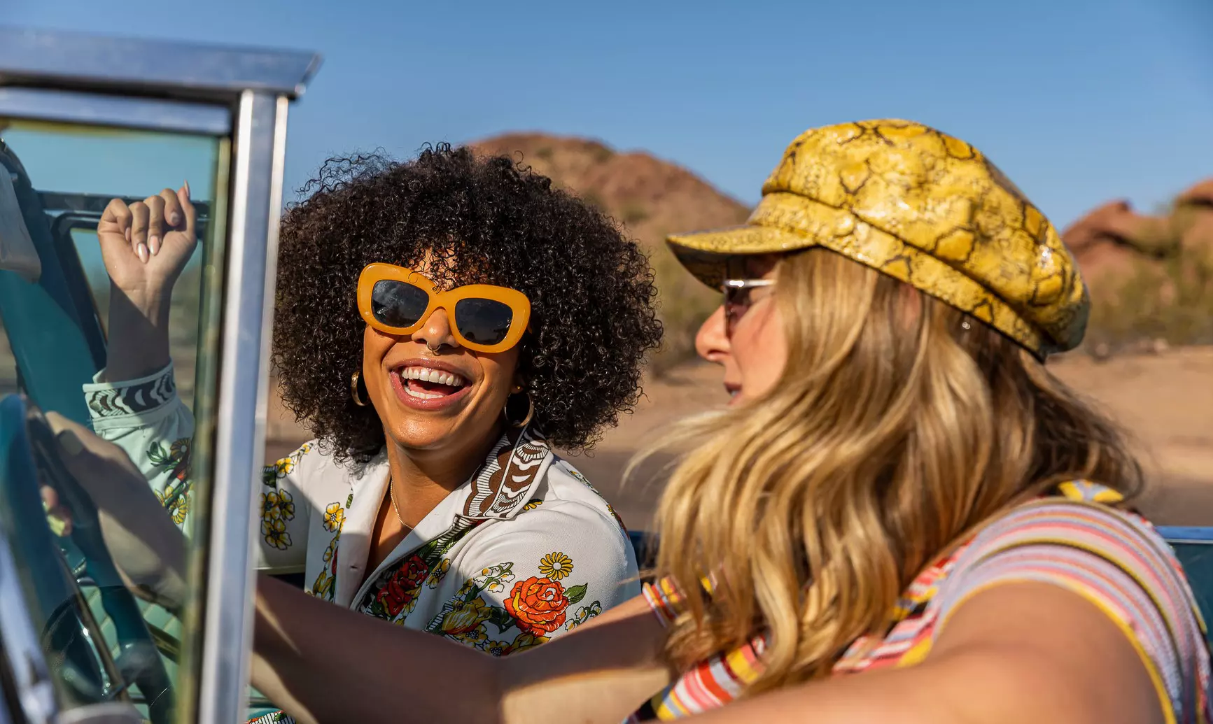 Two boys in red t-shirts stare through a wall of steel bars heavily covered in graffiti with chicken wire on the top