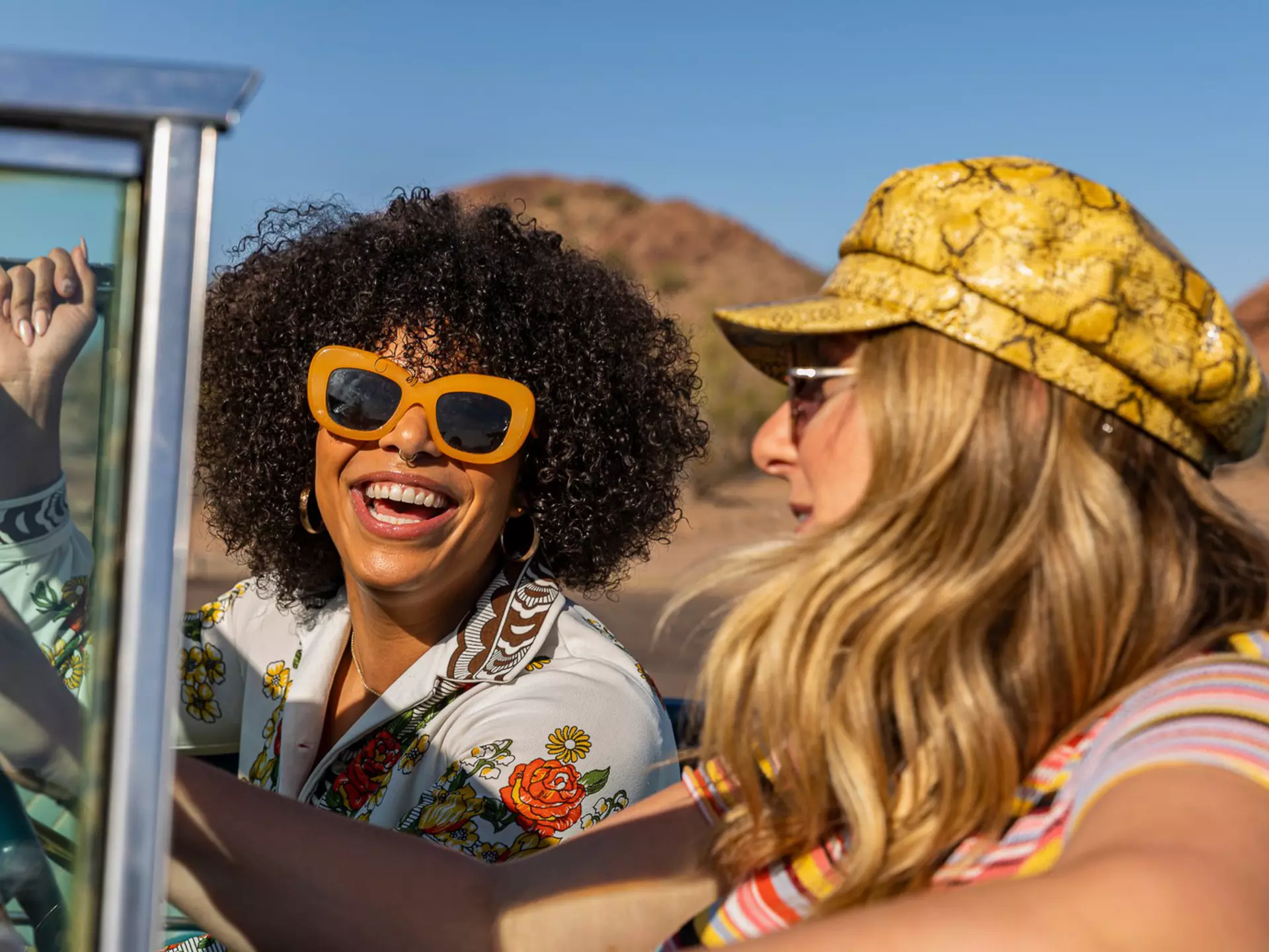 Two boys in red t-shirts stare through a wall of steel bars heavily covered in graffiti with chicken wire on the top