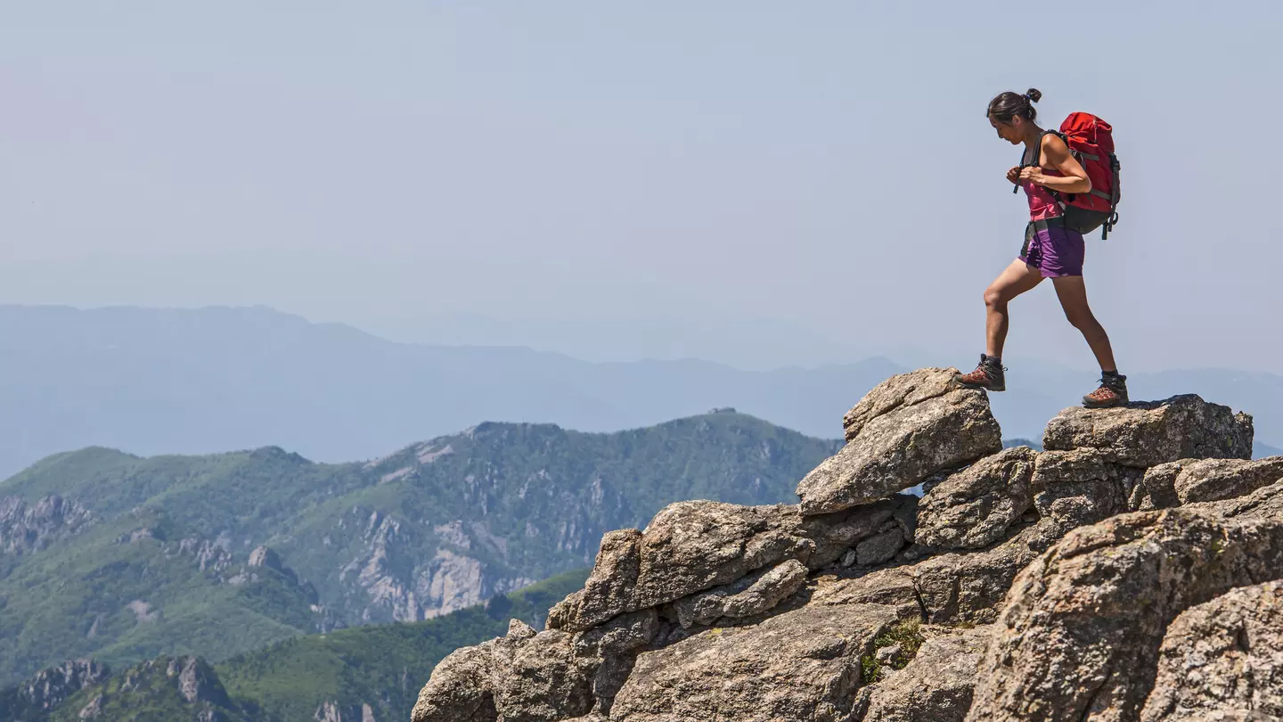 A woman walks across rocky terrain towards Daecheongbong peak at Seoraksan national park