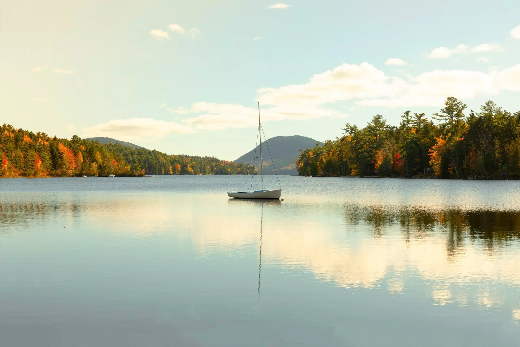 Small sailboat on a lake surrounded by woodland