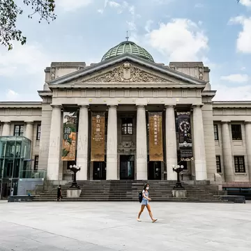 A girl walks in front of the Romanesque columned facade of the National Taiwan Museum in Taipei.