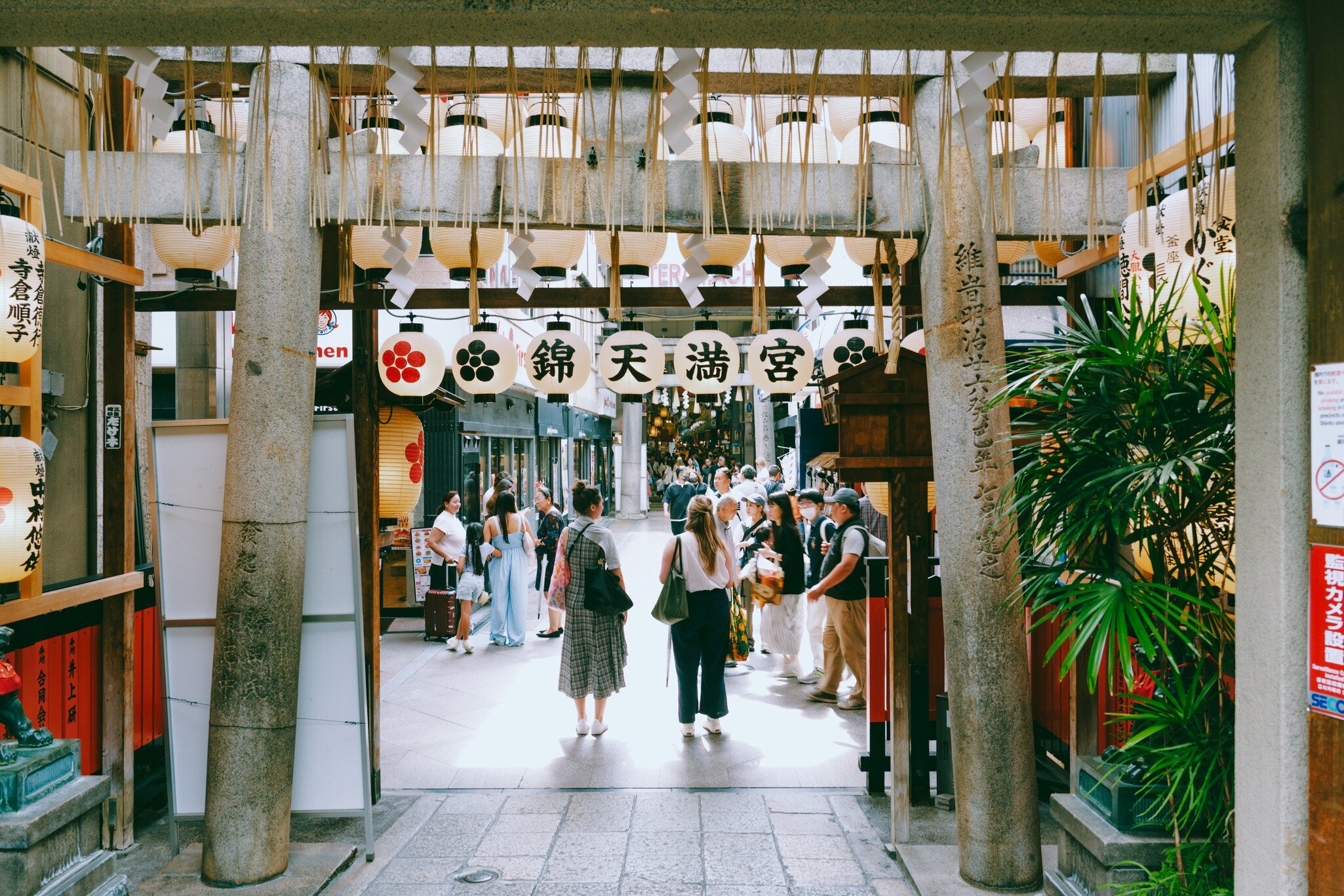 People walk through an entryway with dangling lanterns. 