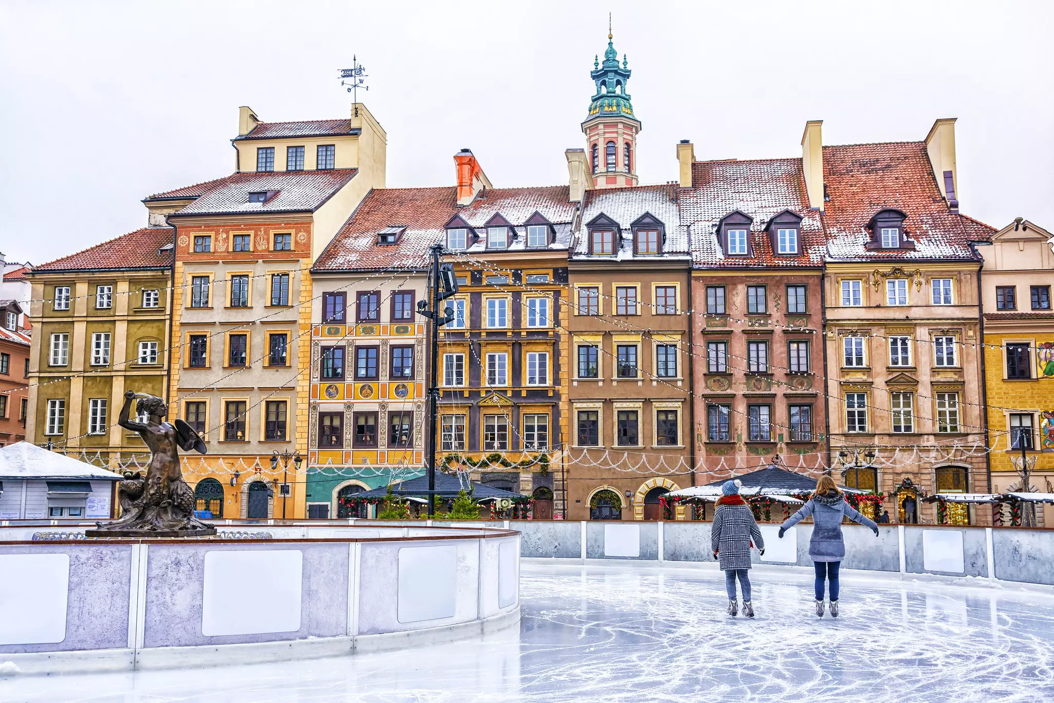 Two people ice-skating on an outdoor rink in a square in Warsaw, Poland.