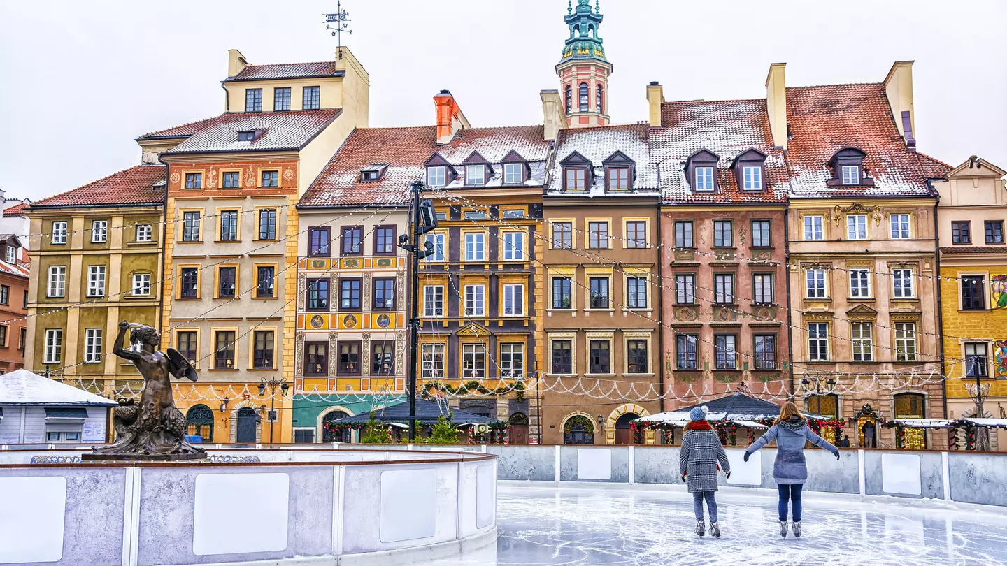 Two people ice-skating on an outdoor rink in a square in Warsaw, Poland.