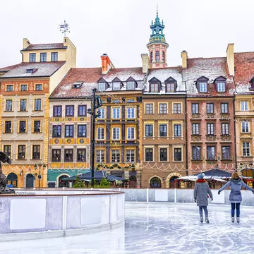 Two people ice-skating on an outdoor rink in a square in Warsaw, Poland.