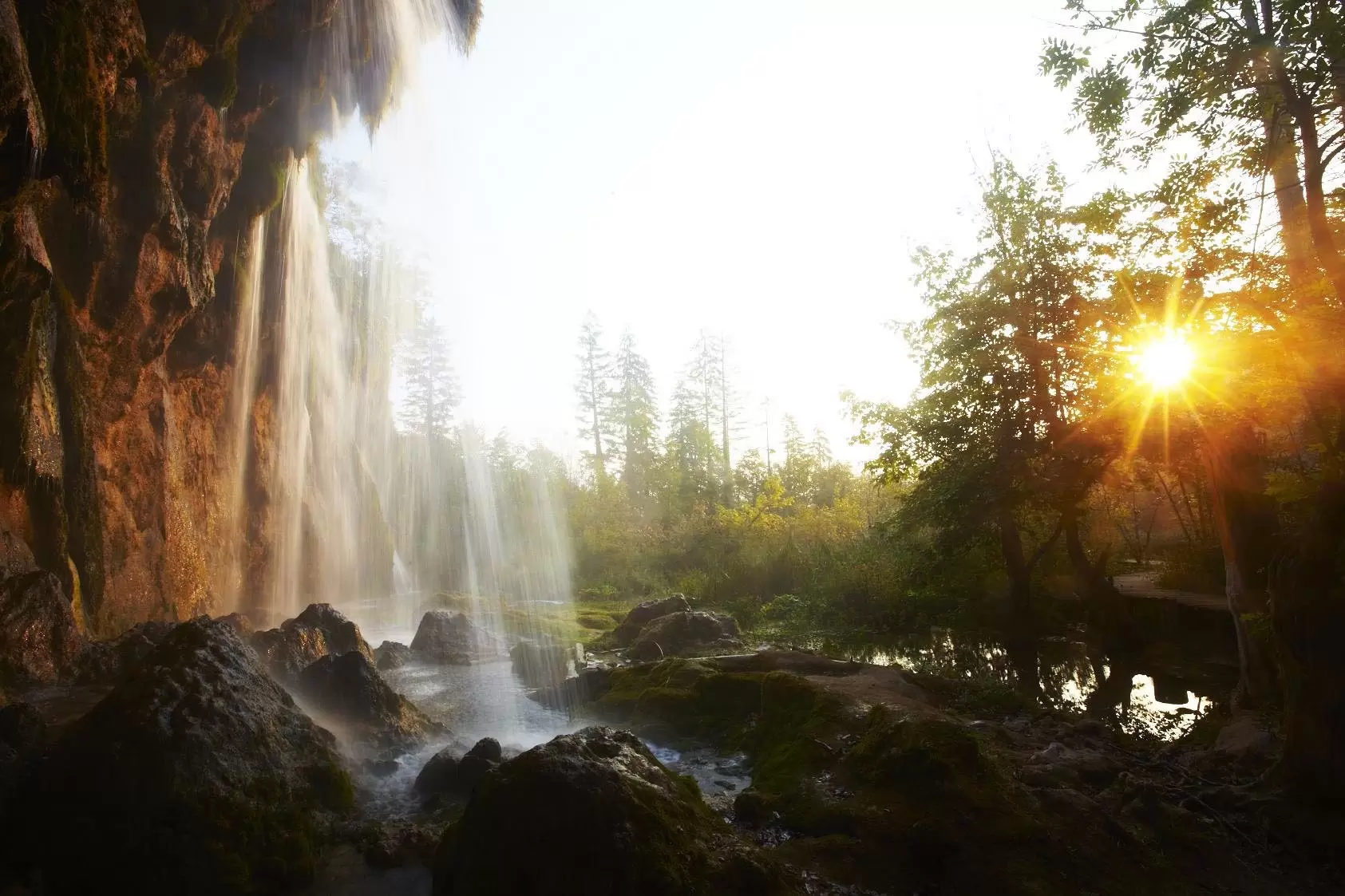 A shot taken from behind a waterfall towards the sun
