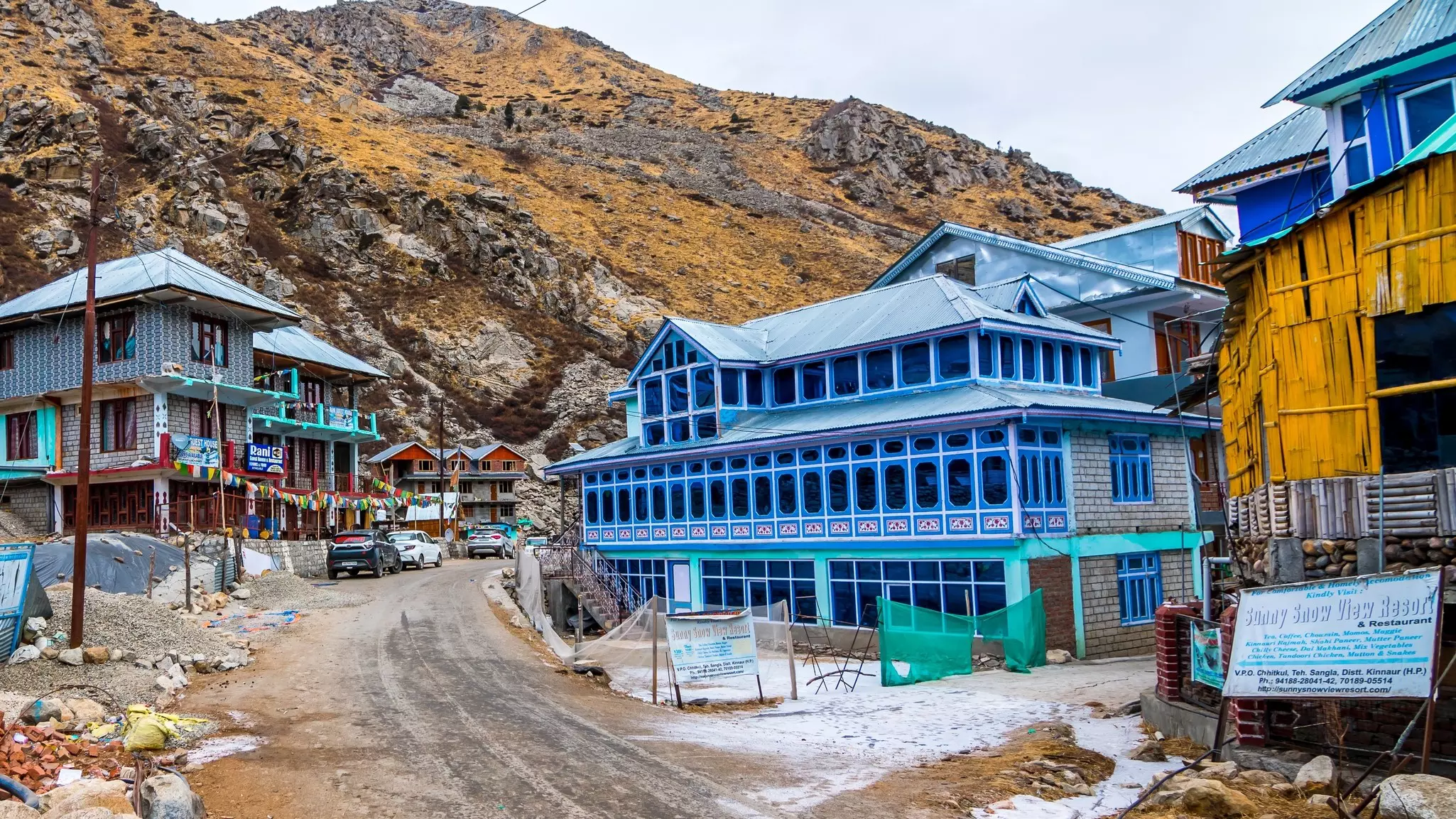 Colorful building along a mostly dirt road, with mountains in the background
