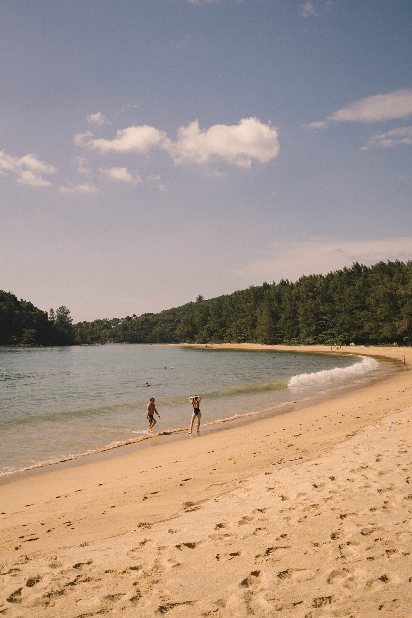 Winding sandy path in Layan Beach, Phuket, Thailand. Two people on shoreline. 