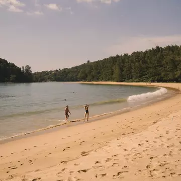 Winding sandy path in Layan Beach, Phuket, Thailand. Two people on shoreline. 