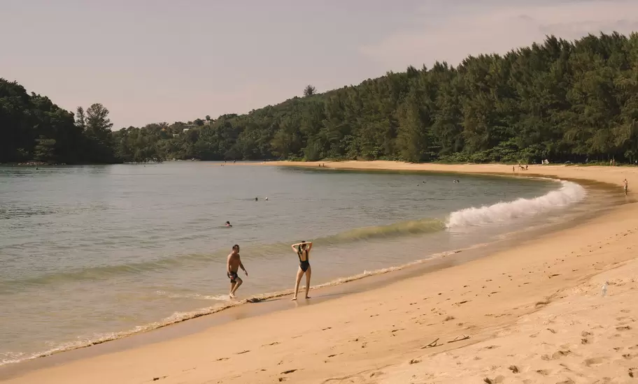 Winding sandy path in Layan Beach, Phuket, Thailand. Two people on shoreline. 