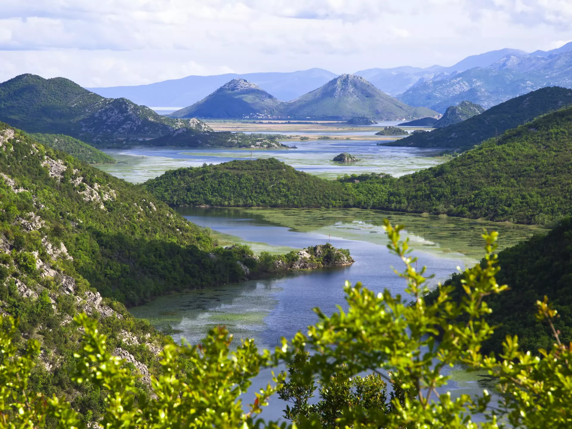 A lake surrounded with green woodland on islands and hills
