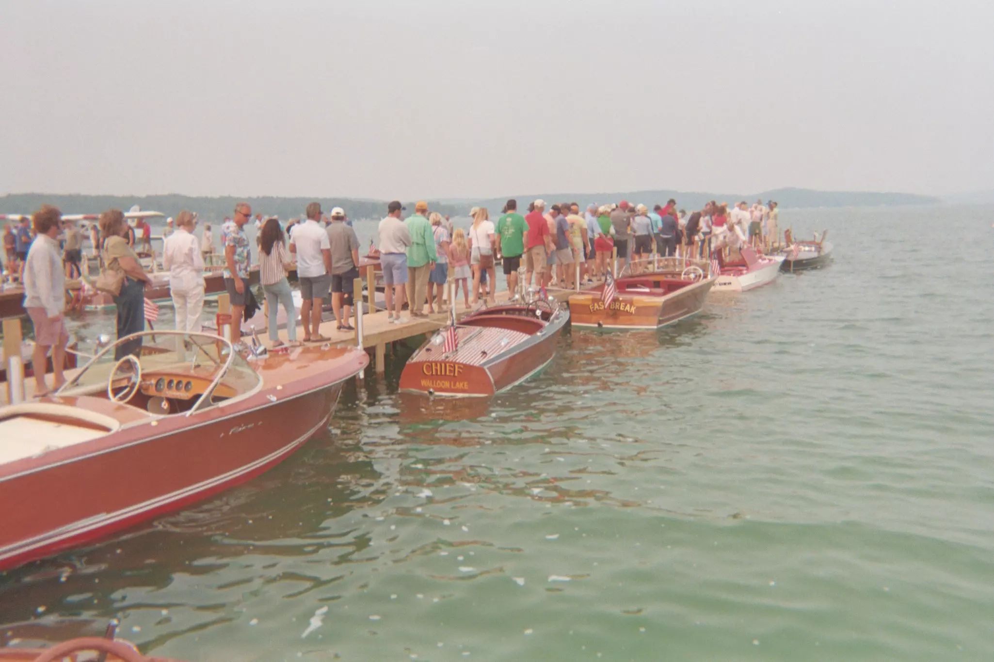 A group of people on a small dock observing boats