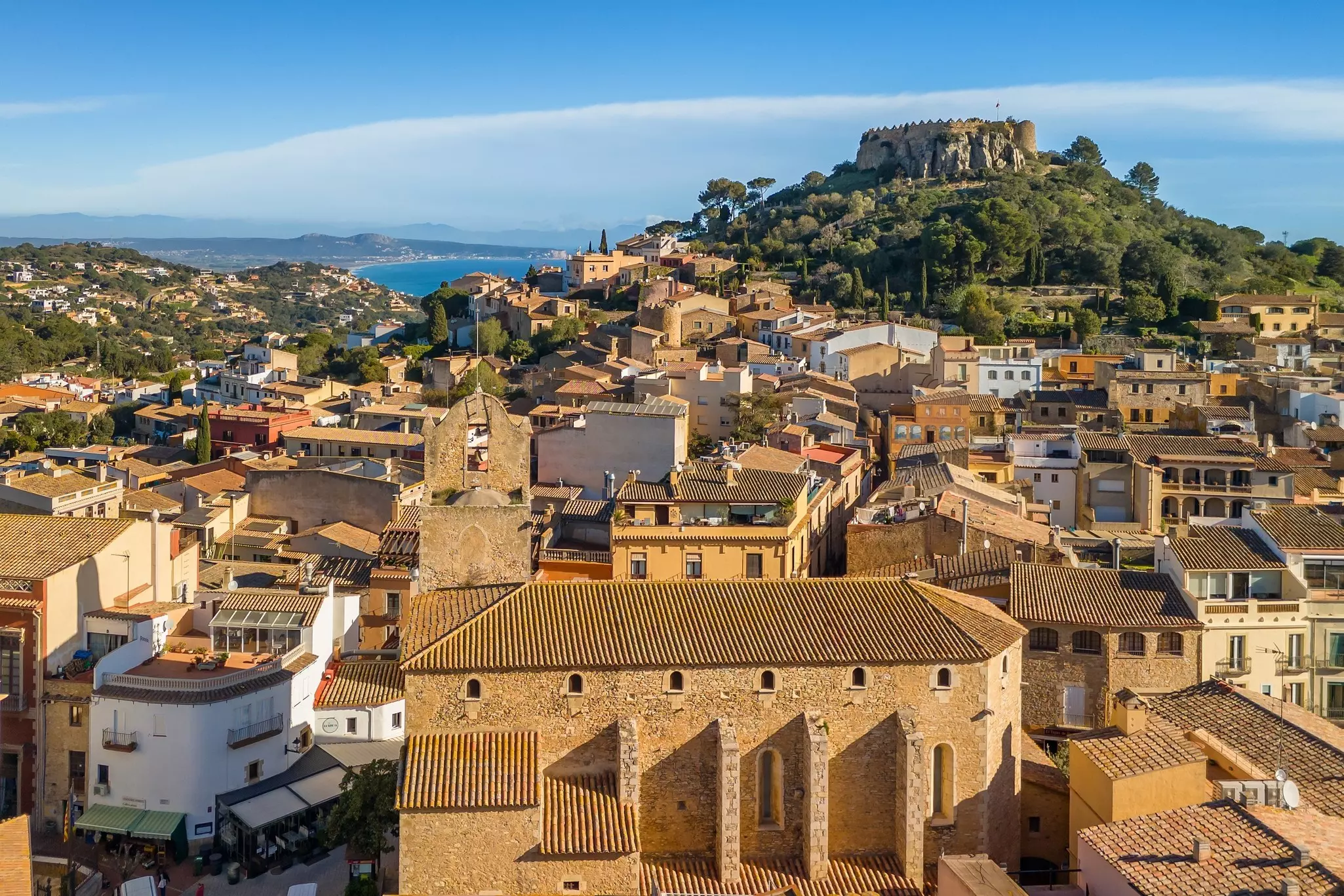 A medieval stone town overlooked by a fortress on a hill.