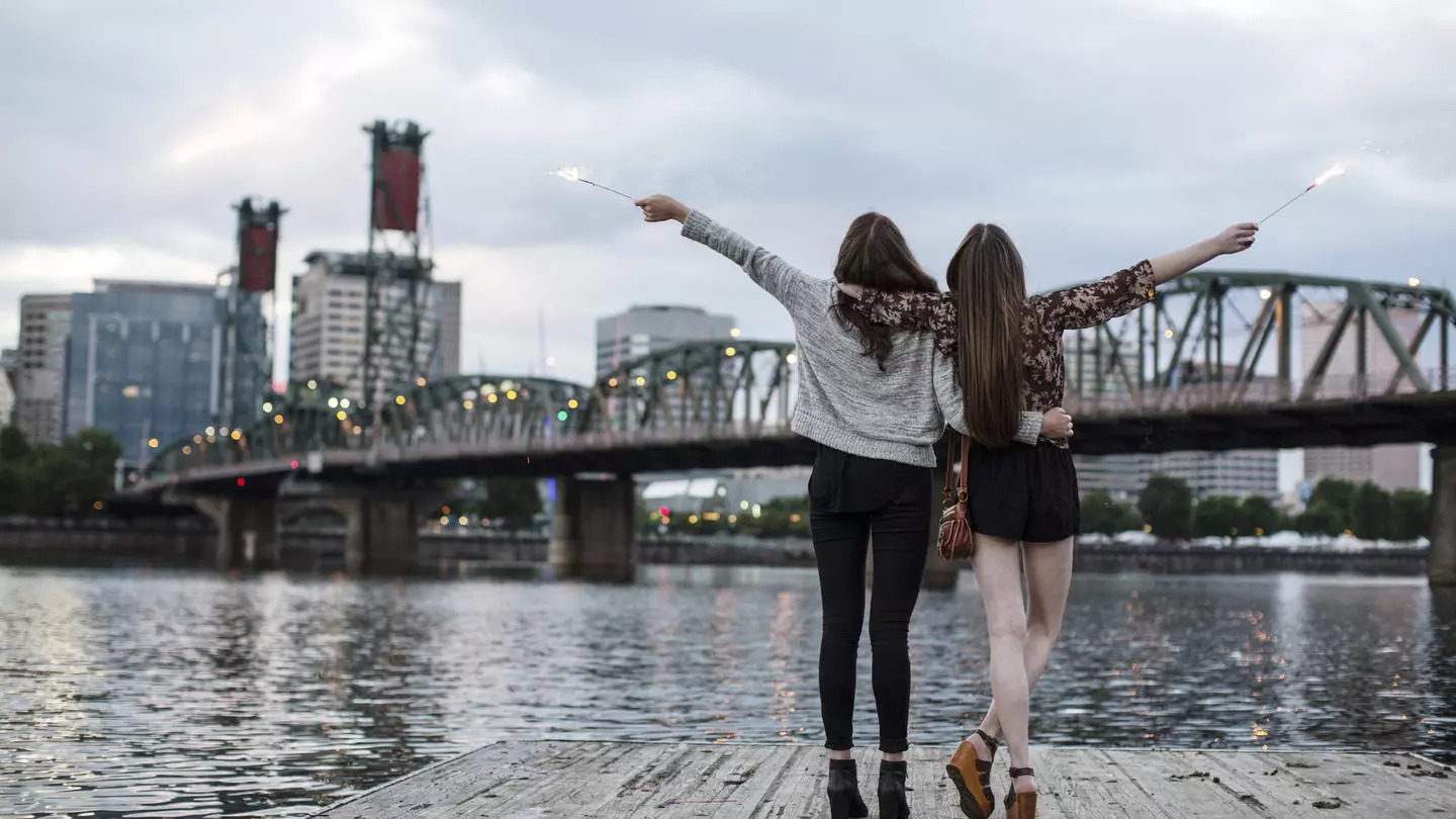 Female friends burning firework while standing against Burlington Northern Railroad Bridge 9.6