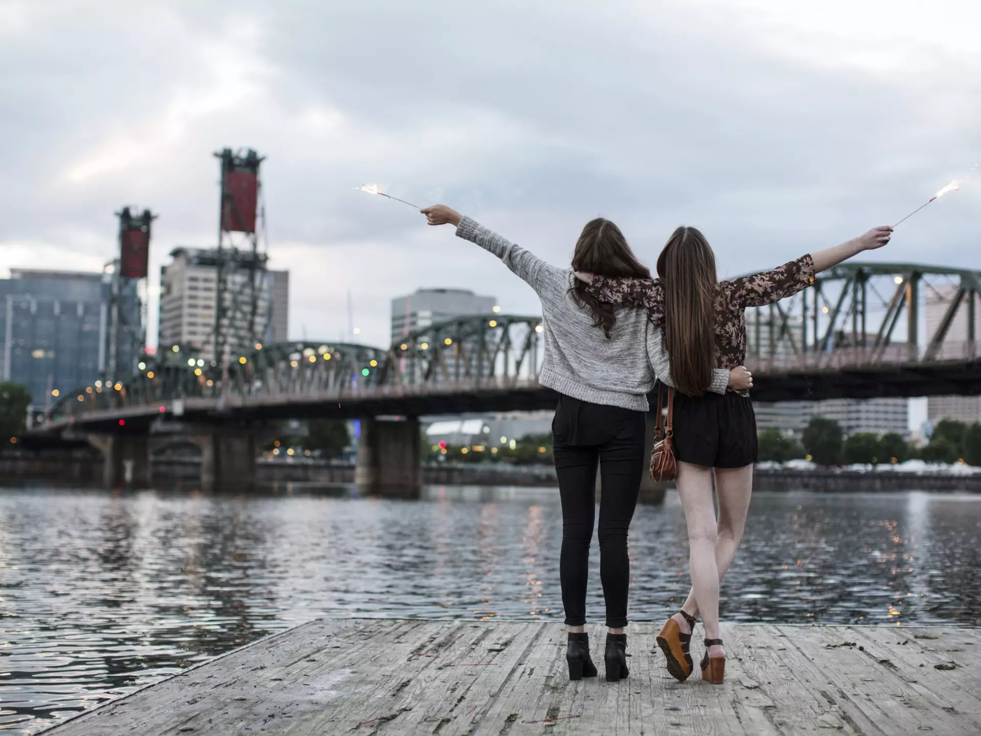Female friends burning firework while standing against Burlington Northern Railroad Bridge 9.6