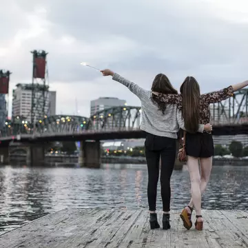 Female friends burning firework while standing against Burlington Northern Railroad Bridge 9.6