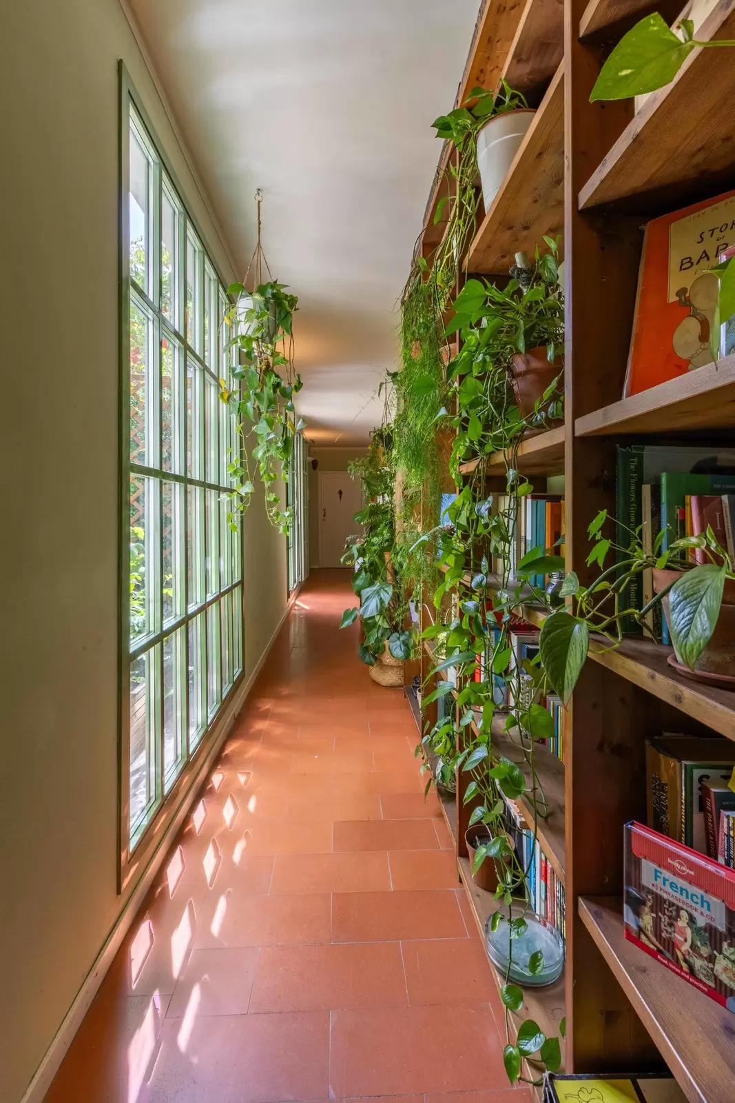 View down a long hallway lined with windows on one side and bookshelves on the other