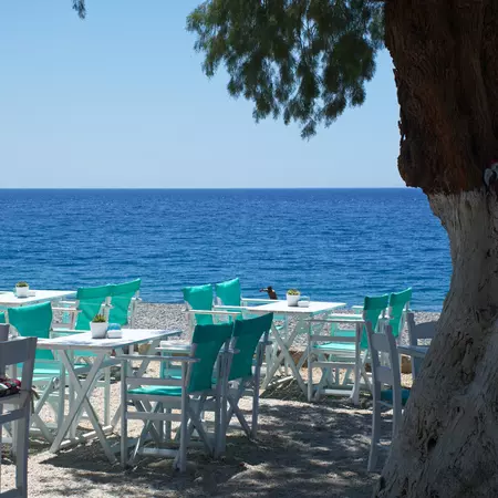 Tavern with white tables and chairs and turquoise tablecloth on the beach
