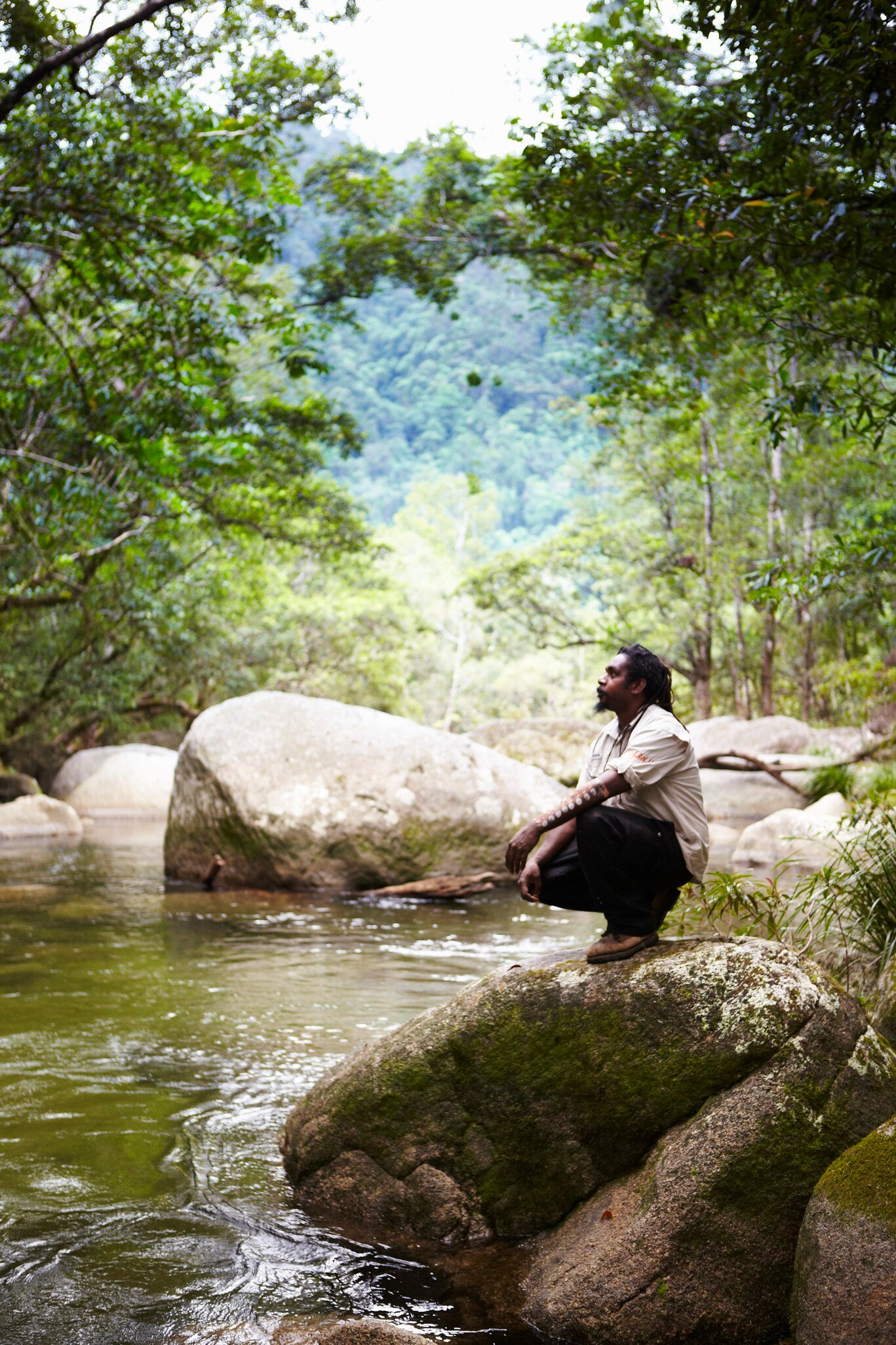 Guide from Kuku Yalanji tribe sitting beside Mossman River. Mossman Gorge, Daintree National Park, Australia.