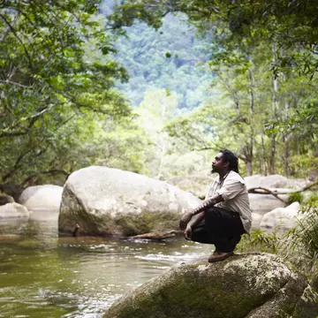 Guide from Kuku Yalanji tribe sitting beside Mossman River. Mossman Gorge, Daintree National Park, Australia.