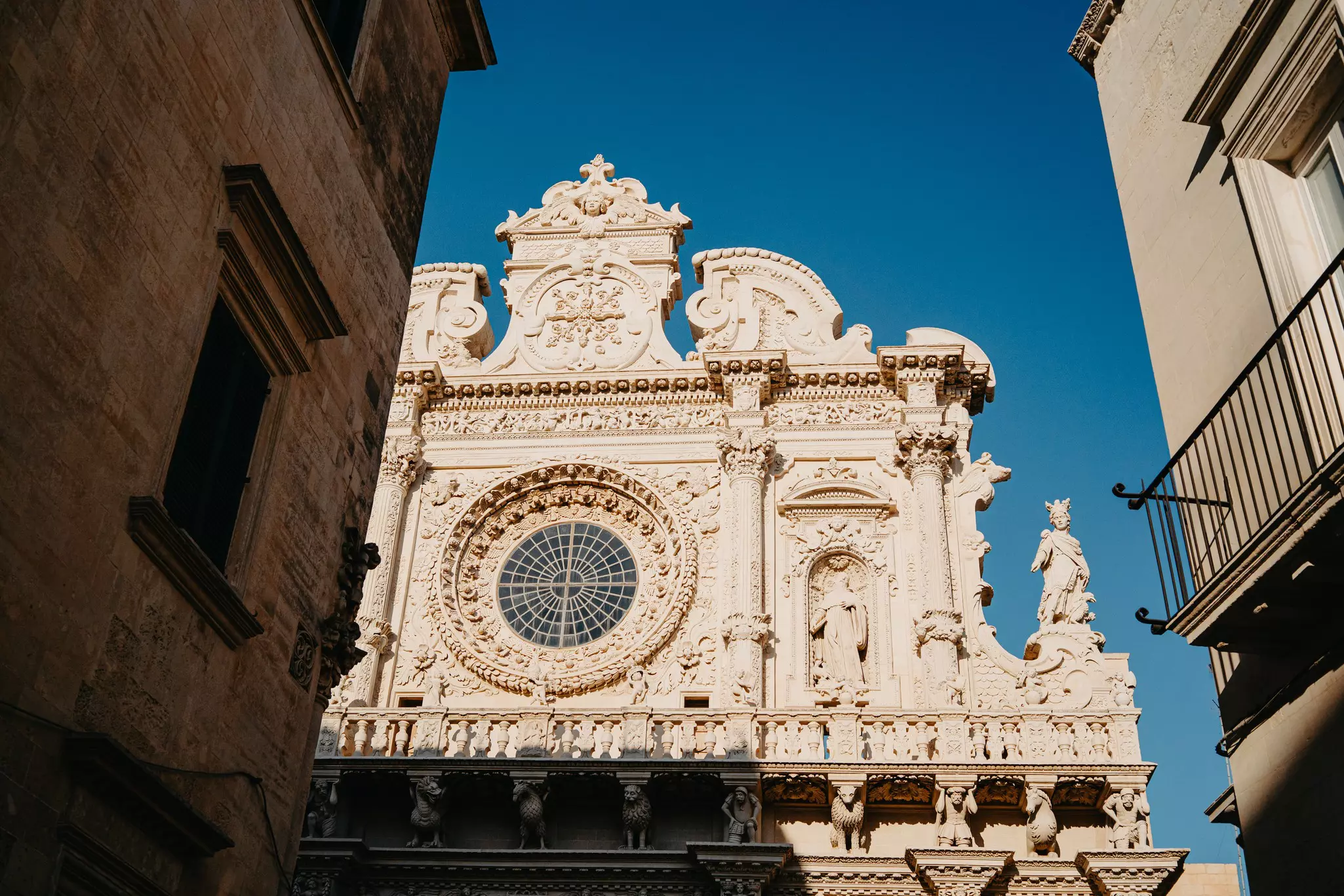 Intricate marble facade of a cathedral with a central rose window.