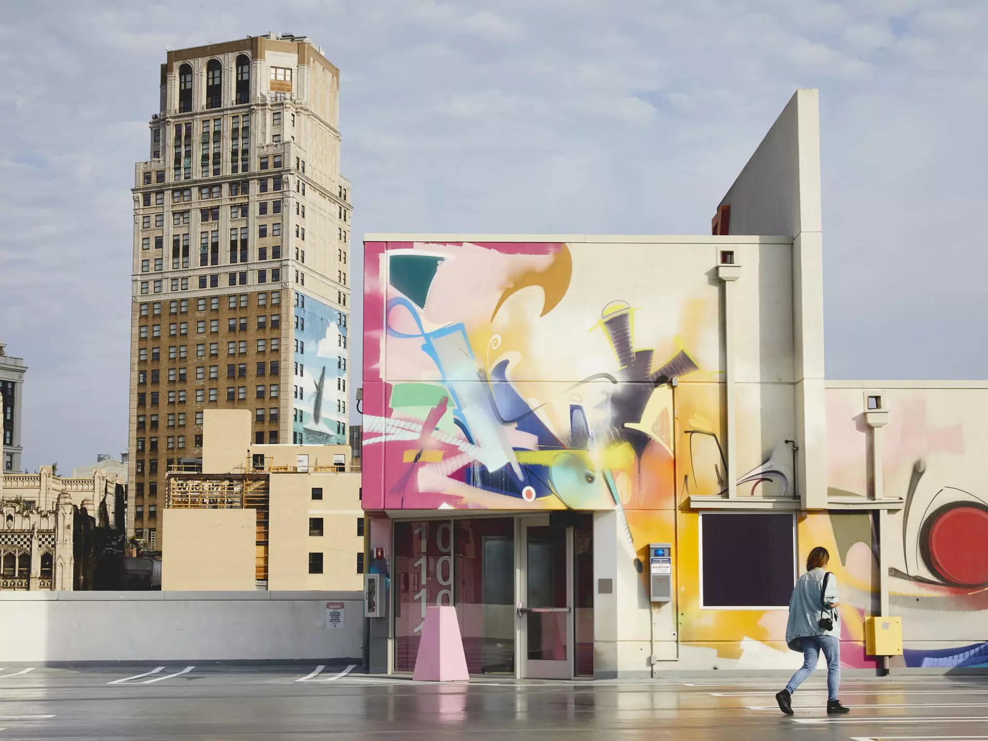 Colourful murals cover the walls of a car park and nearby building.