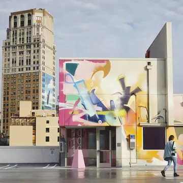 Colourful murals cover the walls of a car park and nearby building.