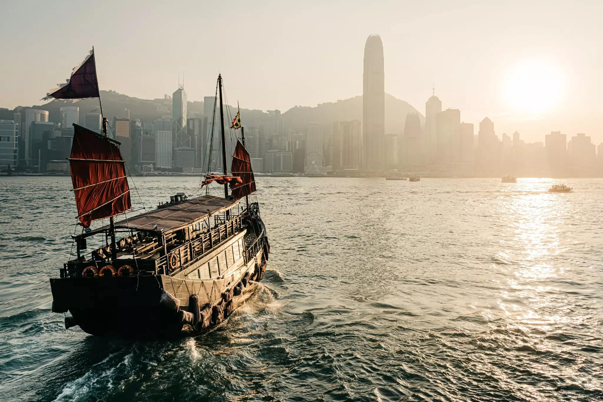 A view across Victoria Harbour to Hong Kong Island, with a junk in the evening light.