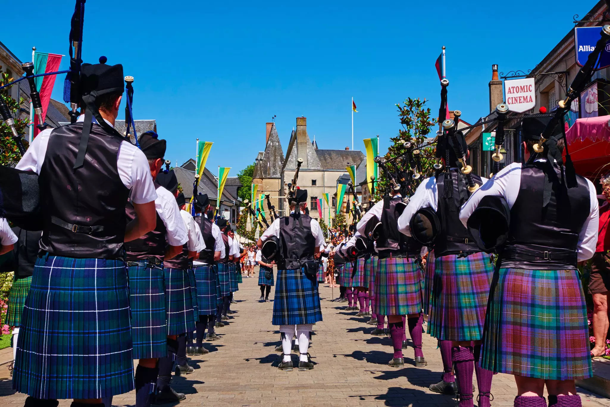 Rows of bagpipe players wearing Scottish kilts prepare to walk down a street in Aubigny-sur-Nère, France.